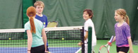 group of kids gather around tennis net