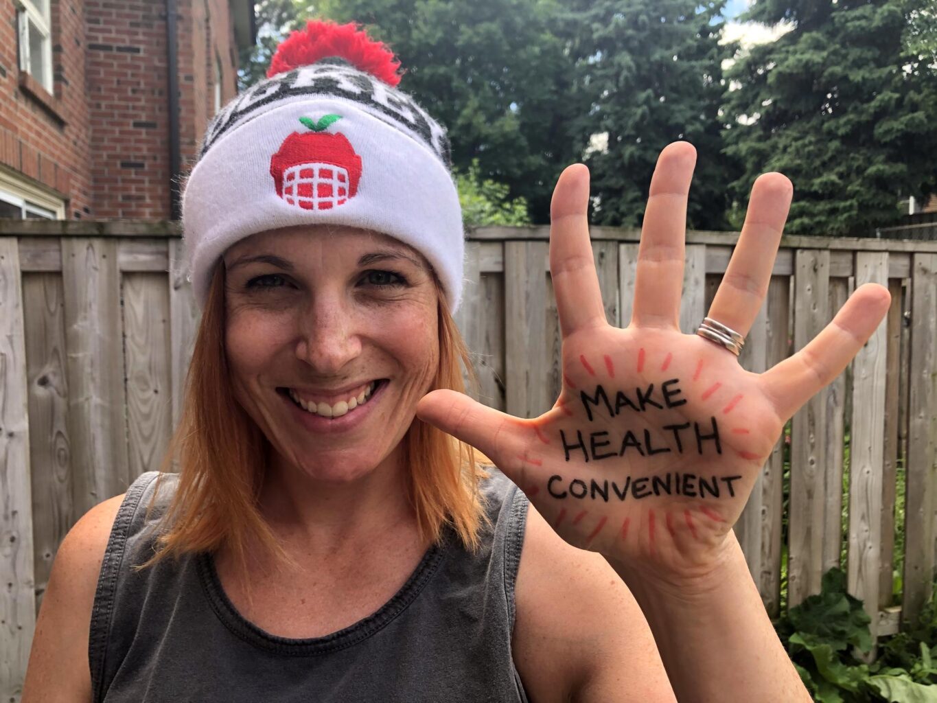 Image of author Seanna Thomas in a hat with the words make health convenient written on her hands in marker