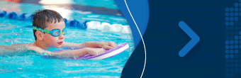 Image of a child kicking in an indoor pool with a flutter board.