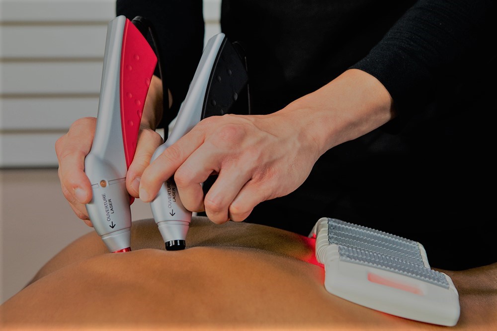 Image of a person applying laser therapy on a client.