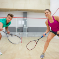 Stock image of a man and woman playing squash on a glass backed squash court.