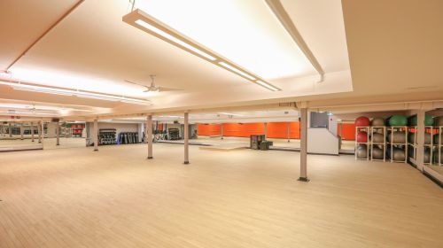 Image of the group exercise studio at Mayfair Parkway. The walls are painted a bright orange and have some walls covered with mirrors. 
