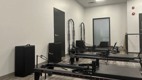 Image of our Pilates Reformer studio at our Mayfair Lakeshore location. There are three Pilates reformer machines in the image.